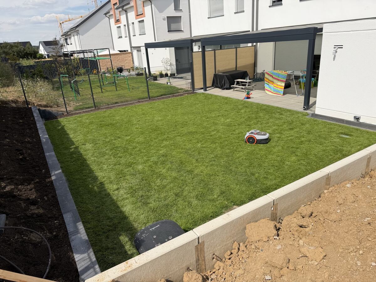 Neu angelegter Garten von oben: Rollrasen, Randeinfassung, Zaun und Terrassenüberdachung