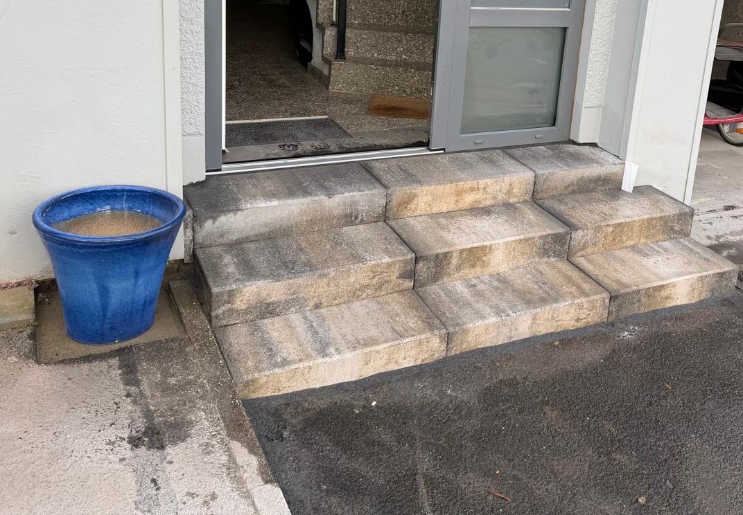 Neu gesetzte Blockstufen-Treppe aus Beton vor einem Hauseingang