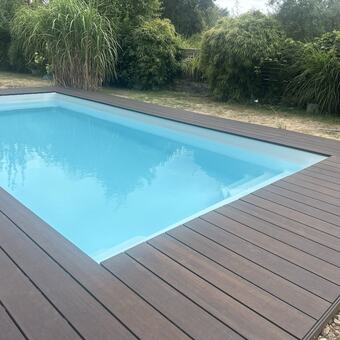 Neues Pooldeck aus dunklen WPC-Dielen rund um einen Gartenpool
